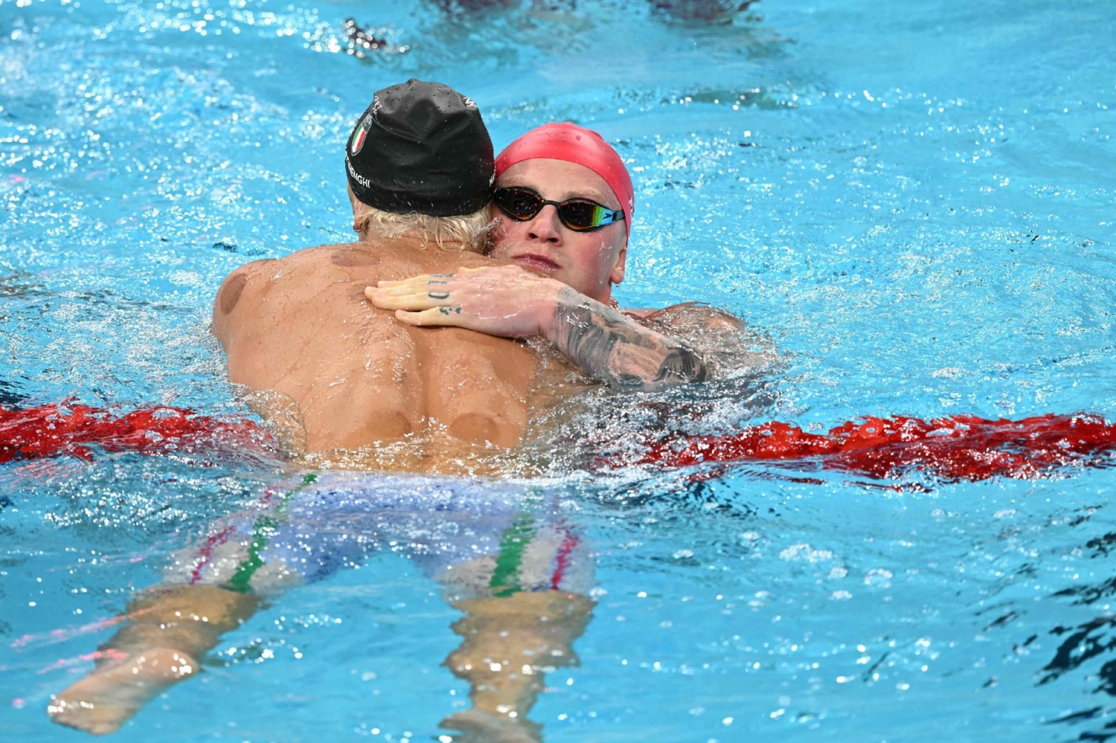 Italy's Nicolo Martinenghi (L) celebrates with Britain's Adam Peaty after winning the final of the men's 100m breaststroke swimming event during the Paris 2024 Olympic Games at the Paris La Defense Arena in Nanterre, west of Paris, on July 28, 2024. (Phot