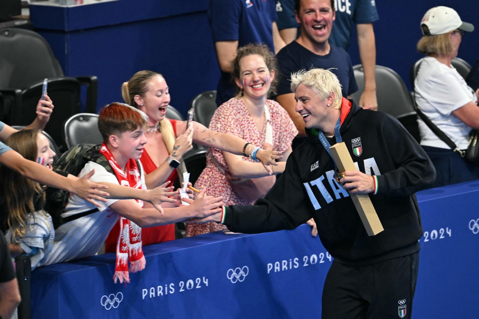 Gold medallist Italy's Nicolo Martinenghi celebrates with fans after the men's 100m breaststroke swimming event during the Paris 2024 Olympic Games at the Paris La Defense Arena in Nanterre, west of Paris, on July 28, 2024. (Photo by Jonathan NACKSTRAND /